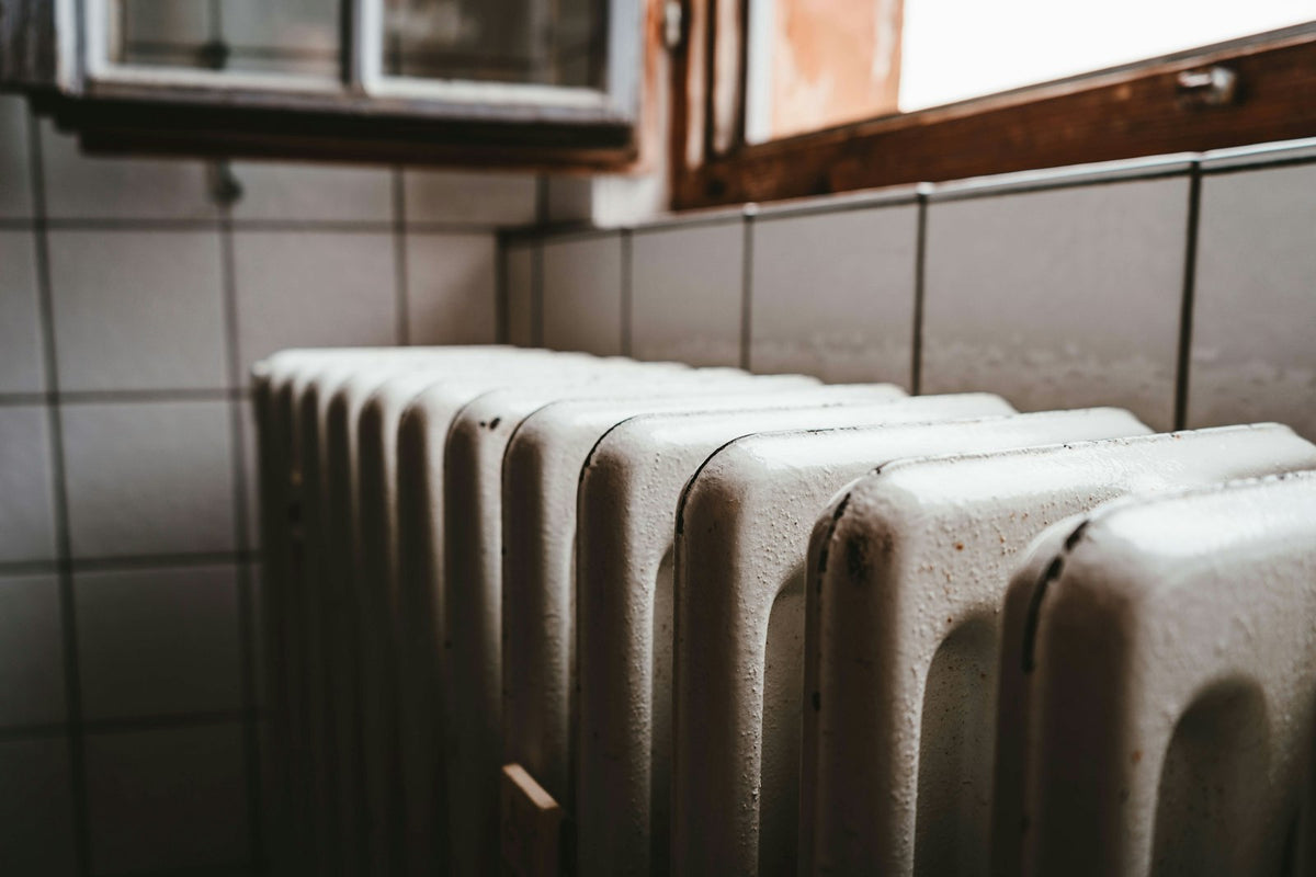 A white radiator beside a wooden window, the central heating that makes modern homes comfortable
