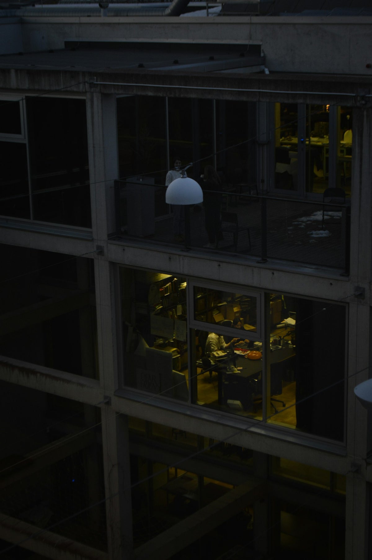 An office interior lit from within, seen through glass windows at night